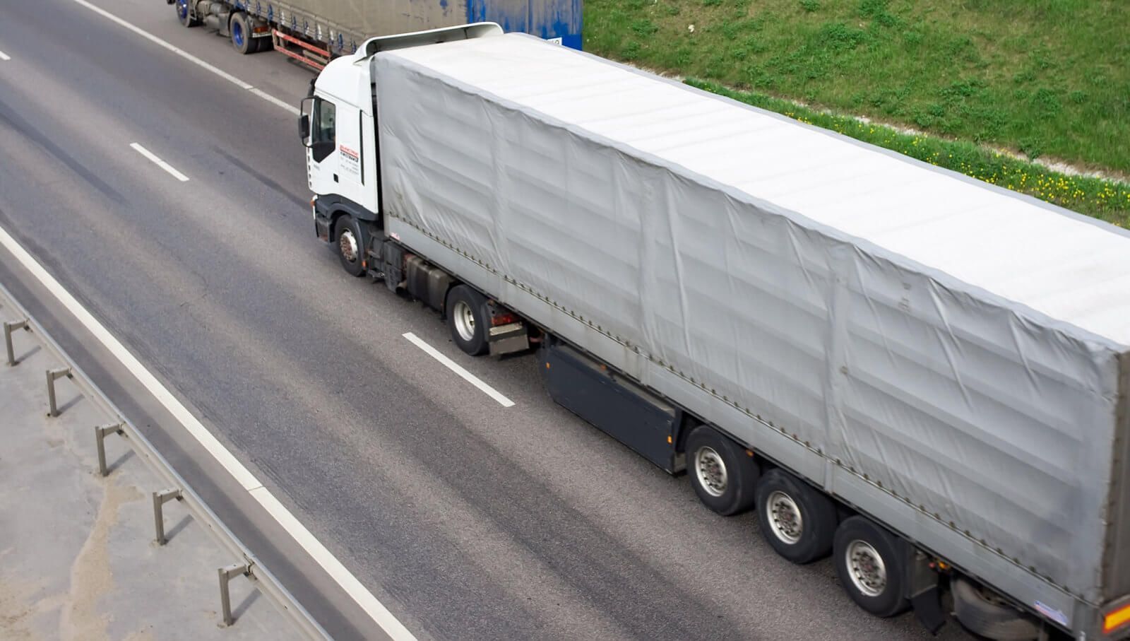 a white truck driving down a highway next to a lush green hillside
