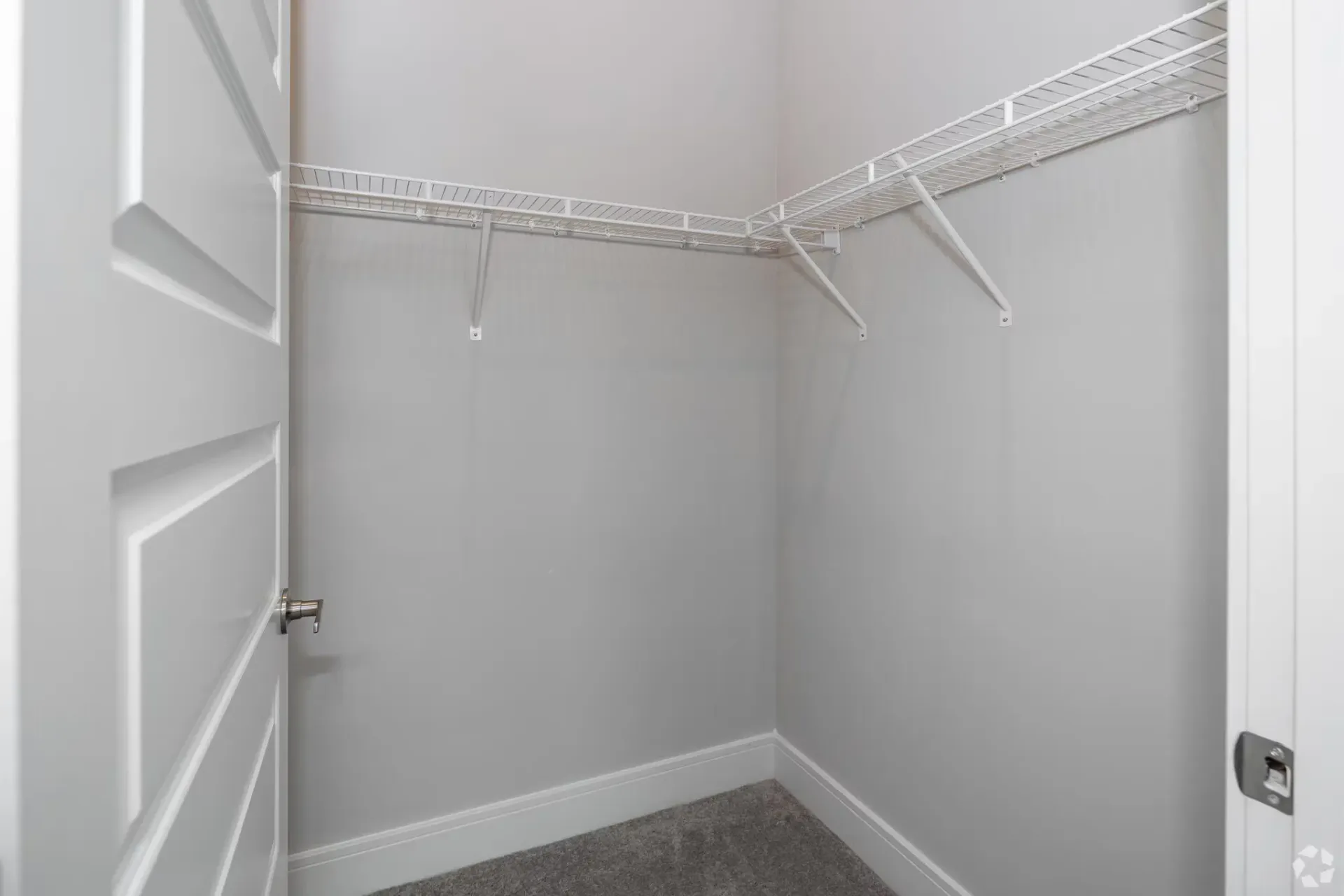 Walk-in closet with white wire shelving and light gray walls.
