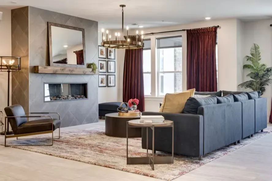 Cozy apartment living room with a dark blue sectional, fireplace, and large windows.
