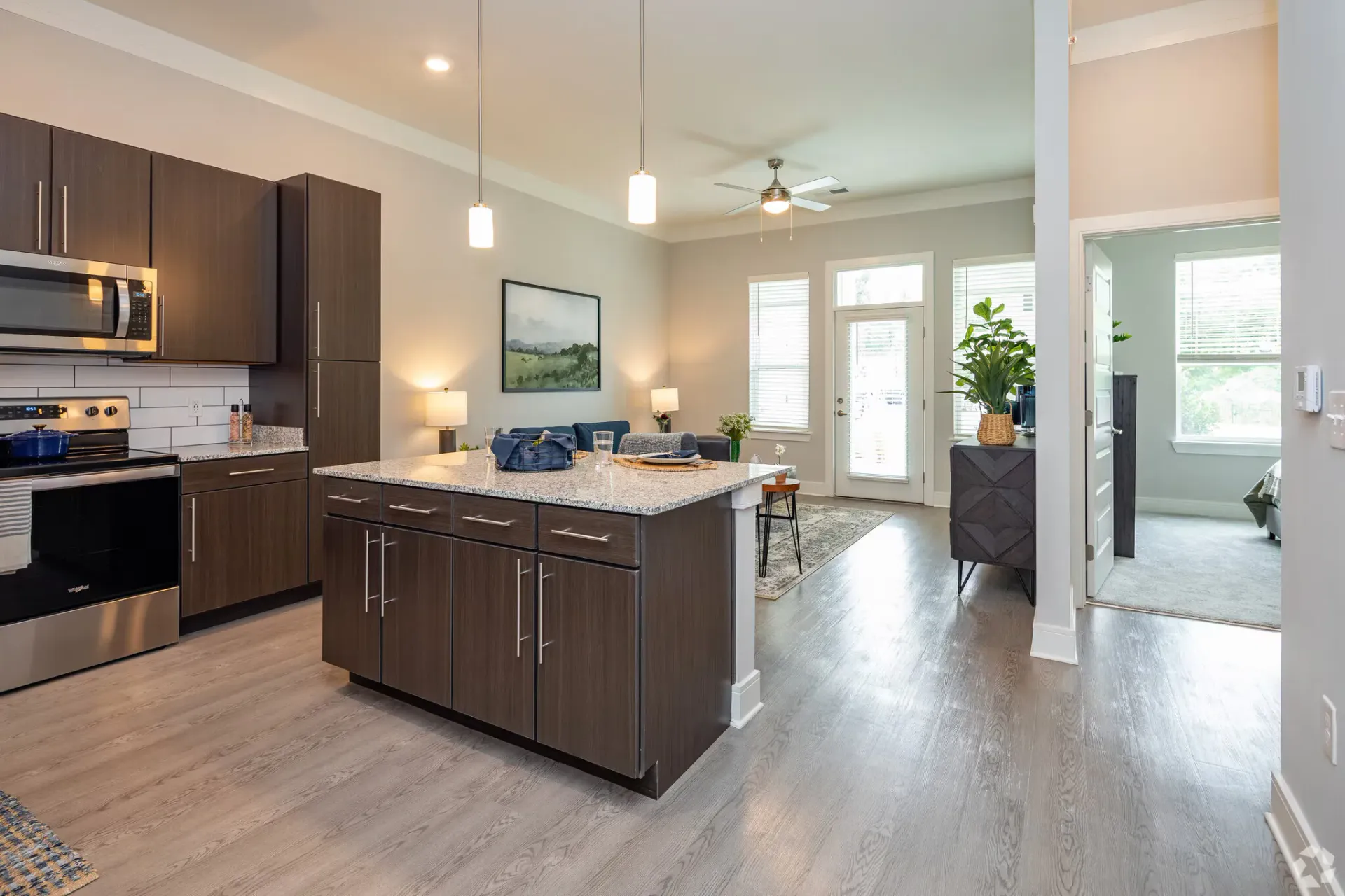 Open-concept kitchen with an island, granite countertops, dark wood cabinets, and adjacent living area.