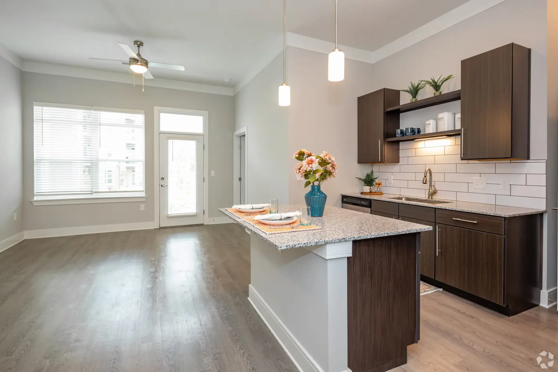 Open-concept kitchen in a modern apartment with island and granite countertops.