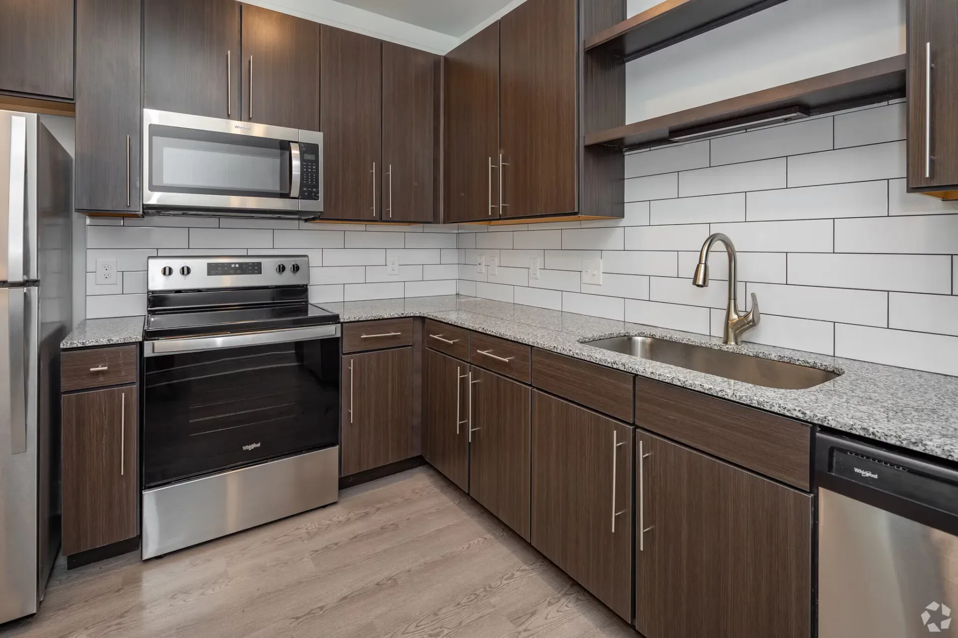 Modern kitchen with dark wood cabinets, granite counters, stainless steel appliances, and subway tile backsplash.