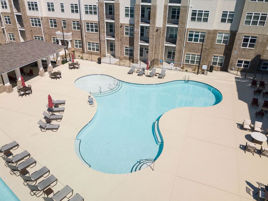 Outdoor pool area at a multifamily community with curved pool shape and lounge seating.