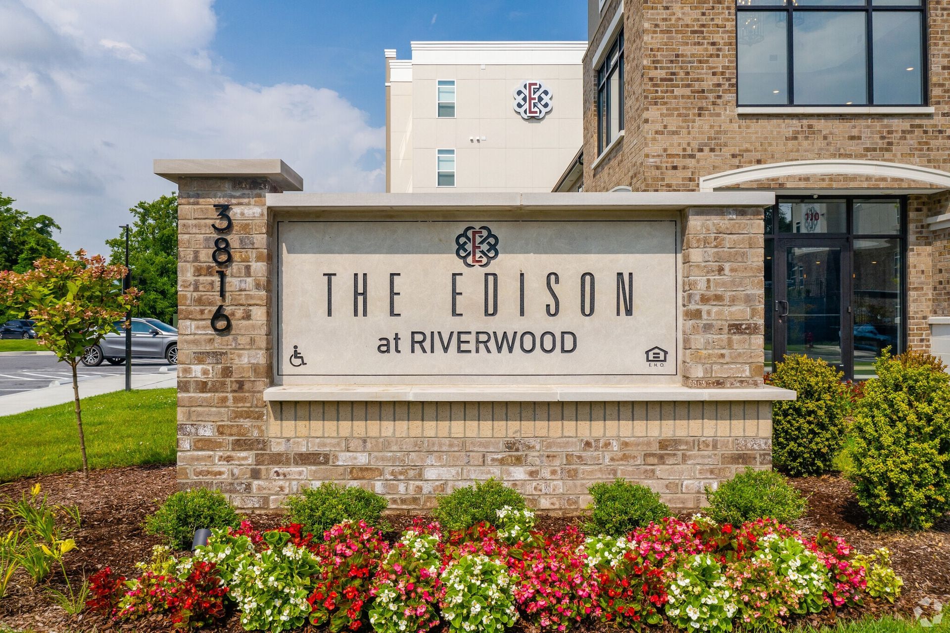 Exterior sign and entrance of The Edison at Riverwood apartment community with brick monument and landscaping.