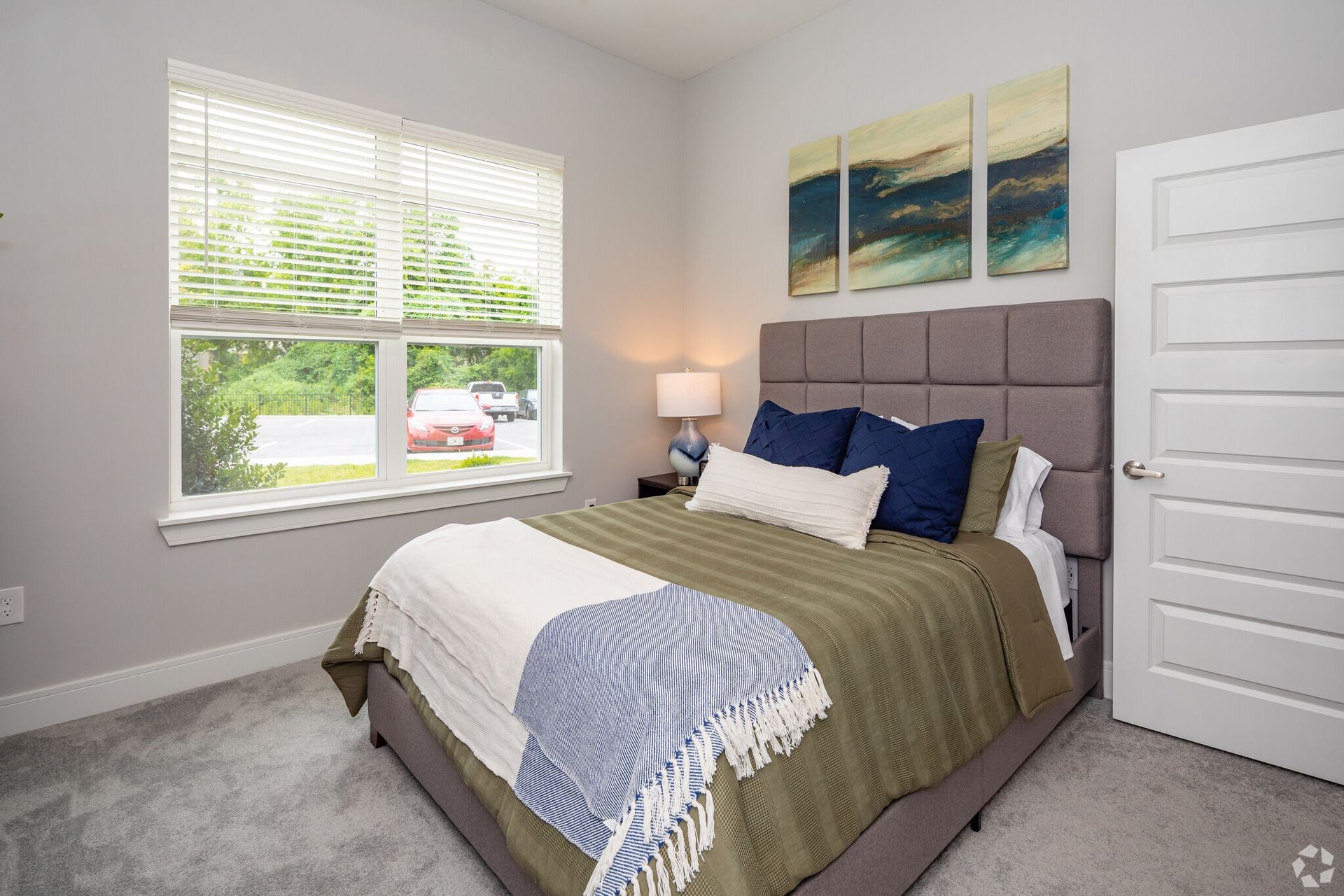 Bedroom in a modern apartment with a padded headboard and large window.