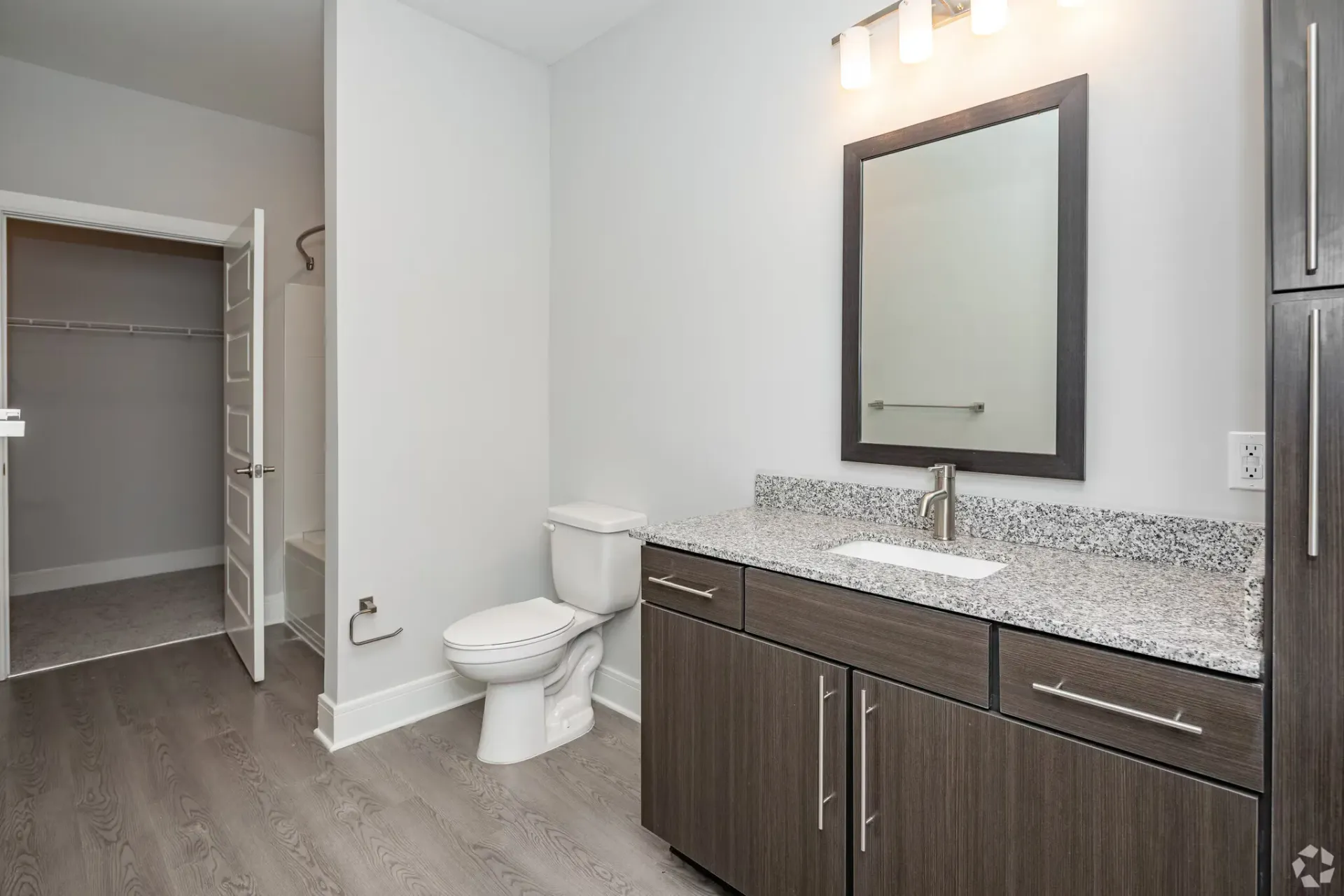 Bathroom with granite vanity, dark wood cabinet, mirror, toilet, and tub/shower.