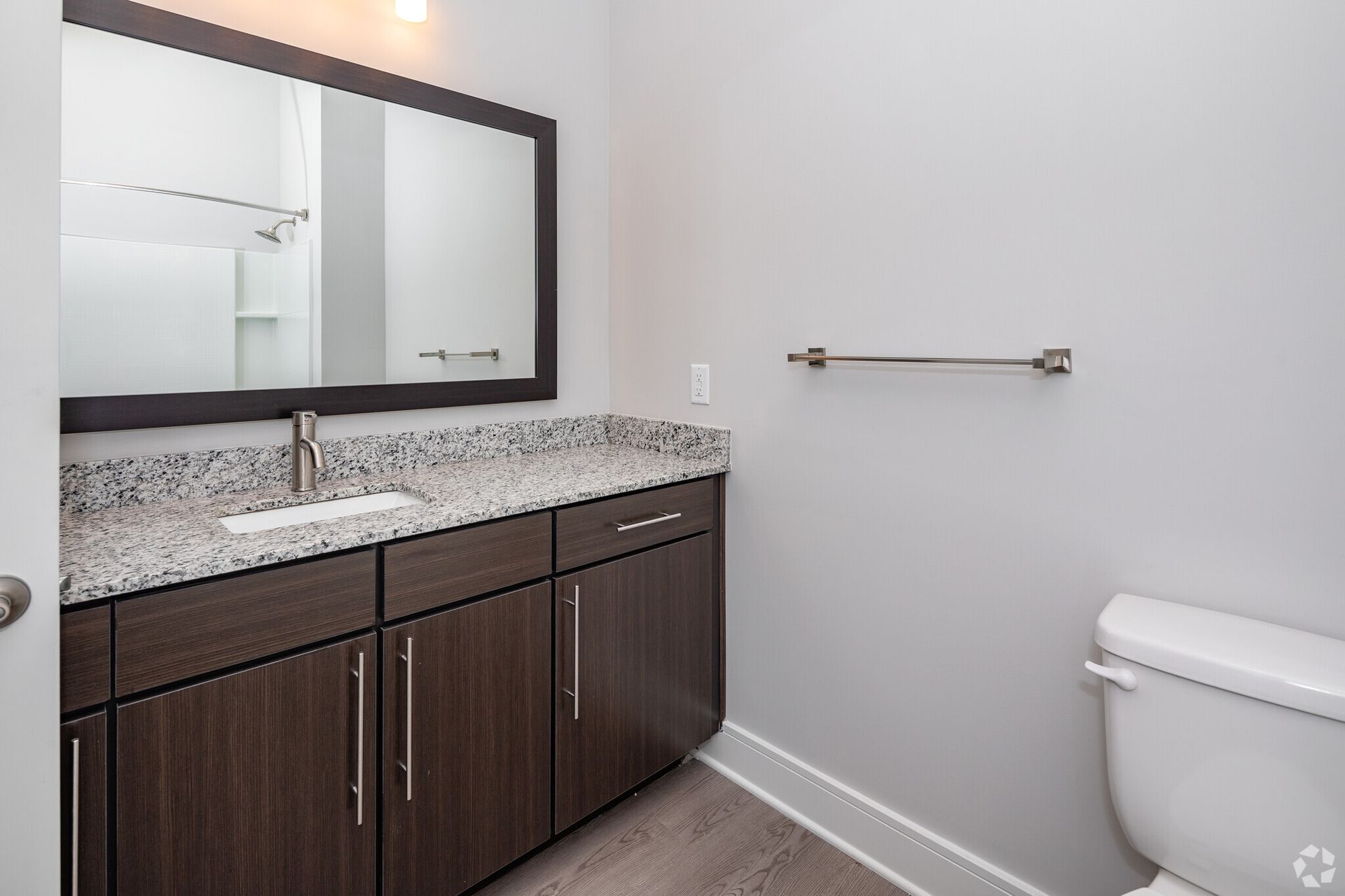 Bathroom with granite countertop vanity, mirror, and toilet.