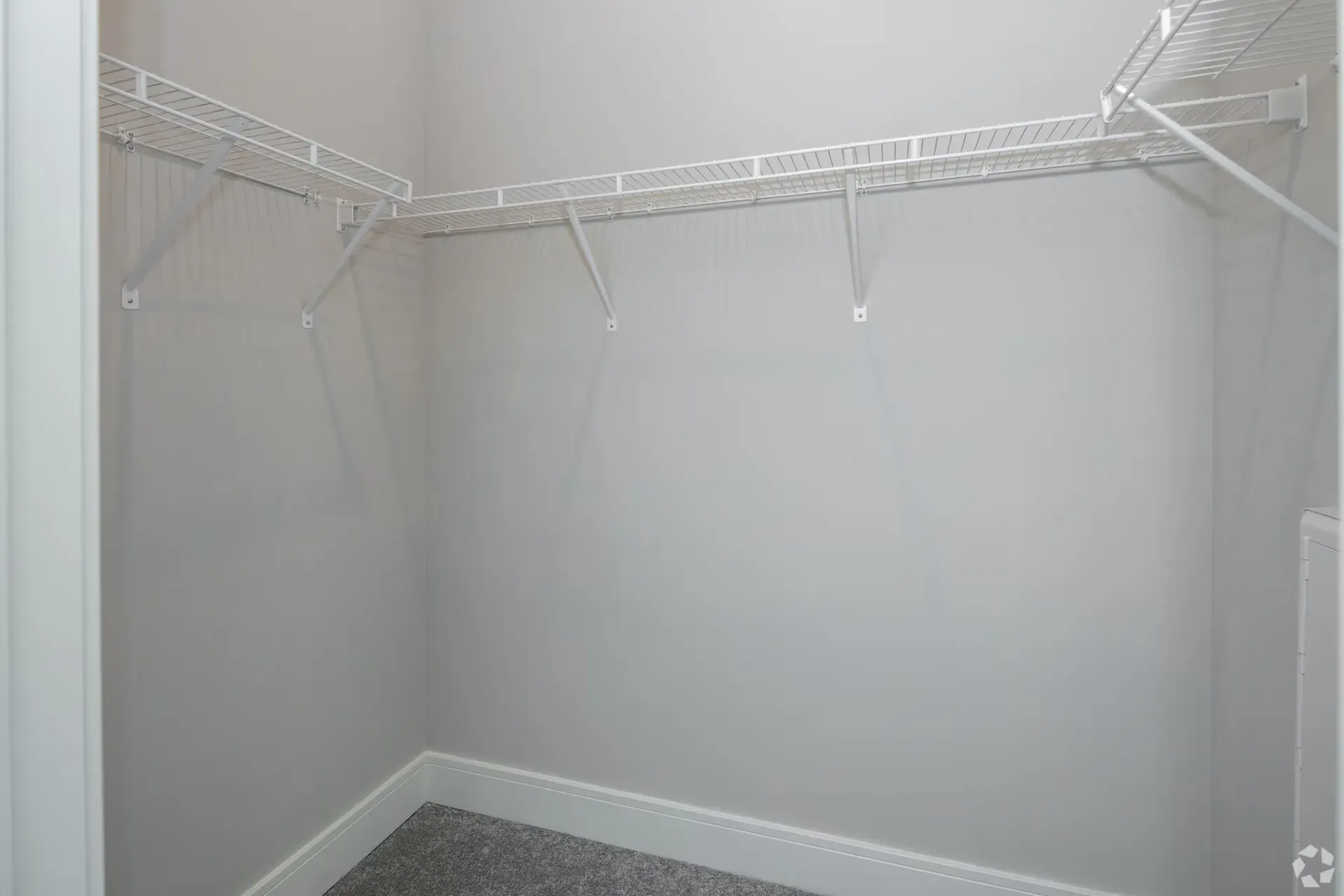 Empty walk-in closet with white wire shelving along the walls.