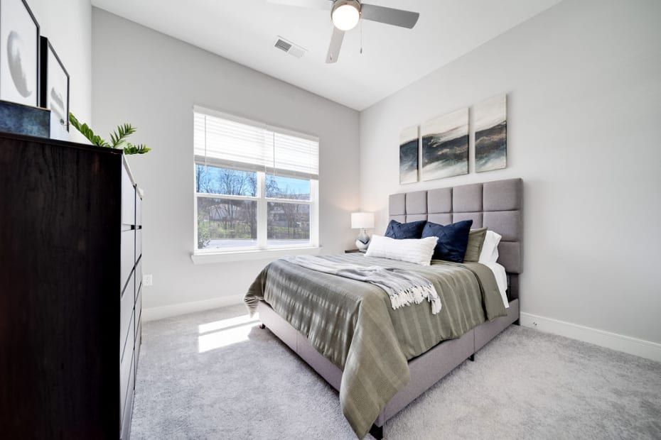Bedroom with gray walls, bed, dresser, window, and abstract art.