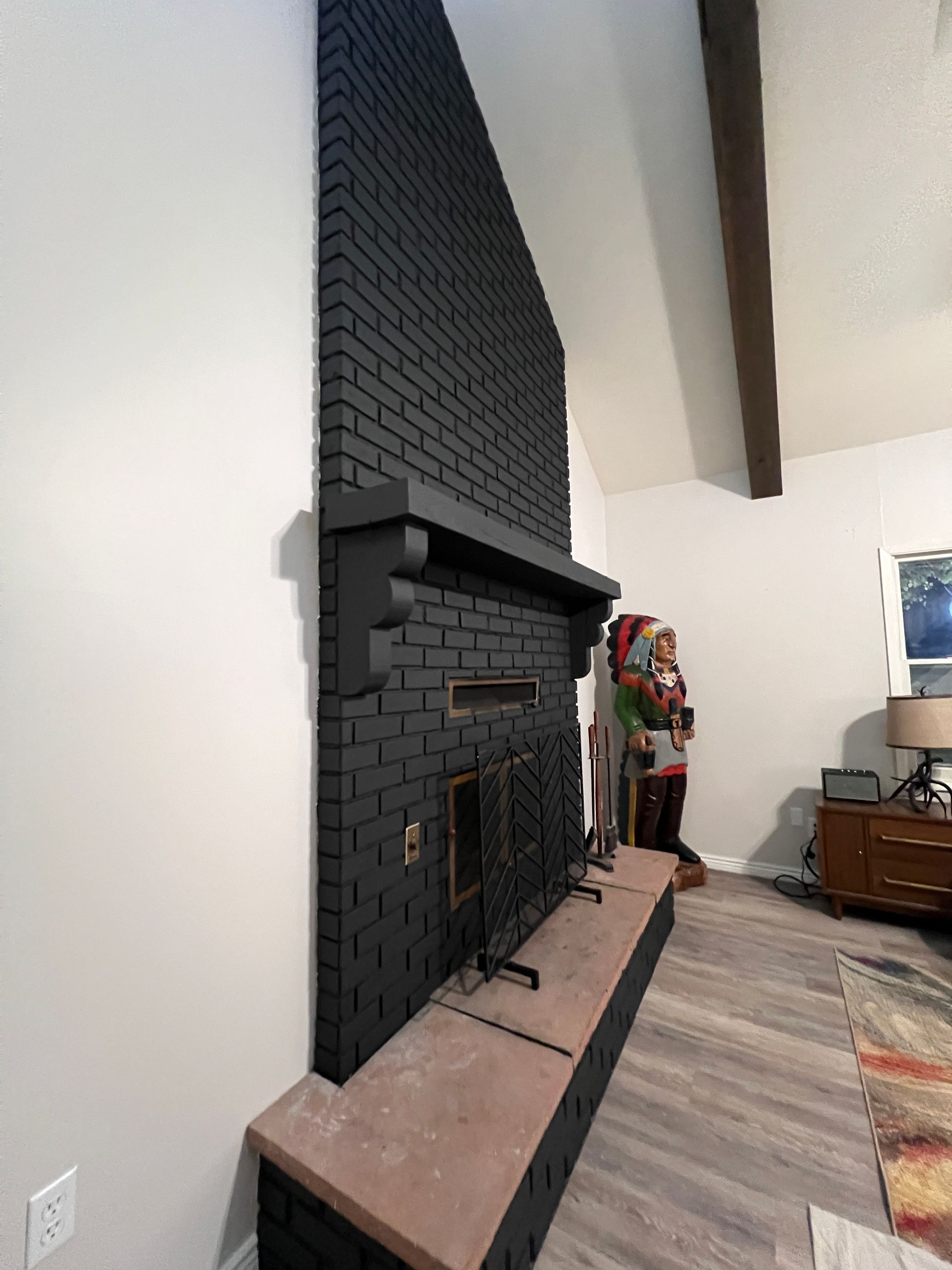 A living room with a black brick fireplace and a santa claus statue.