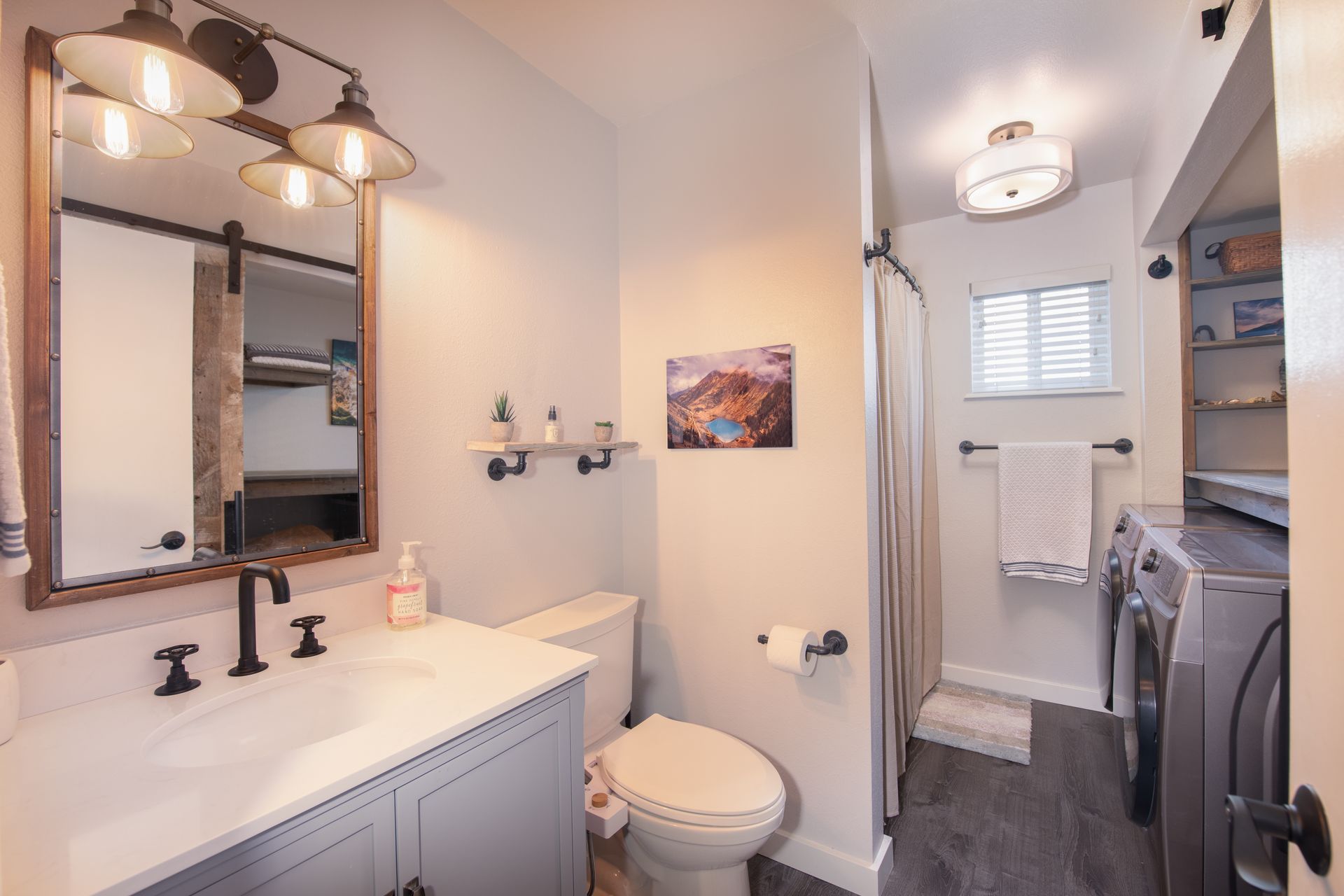 A bathroom with a toilet , sink , mirror and washer and dryer.