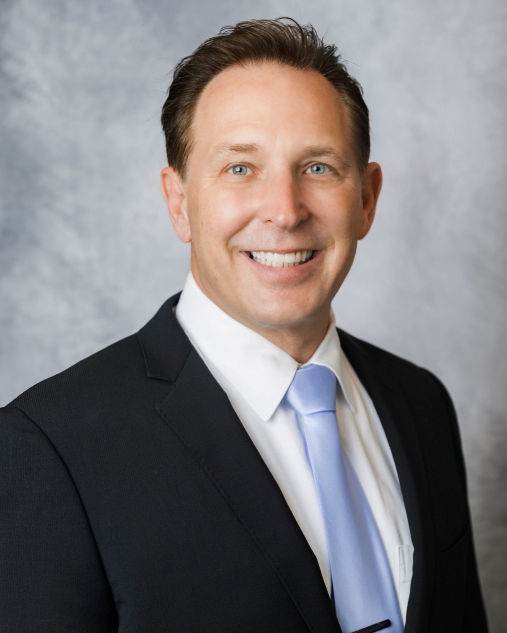 A man in a suit and tie is smiling for the camera.