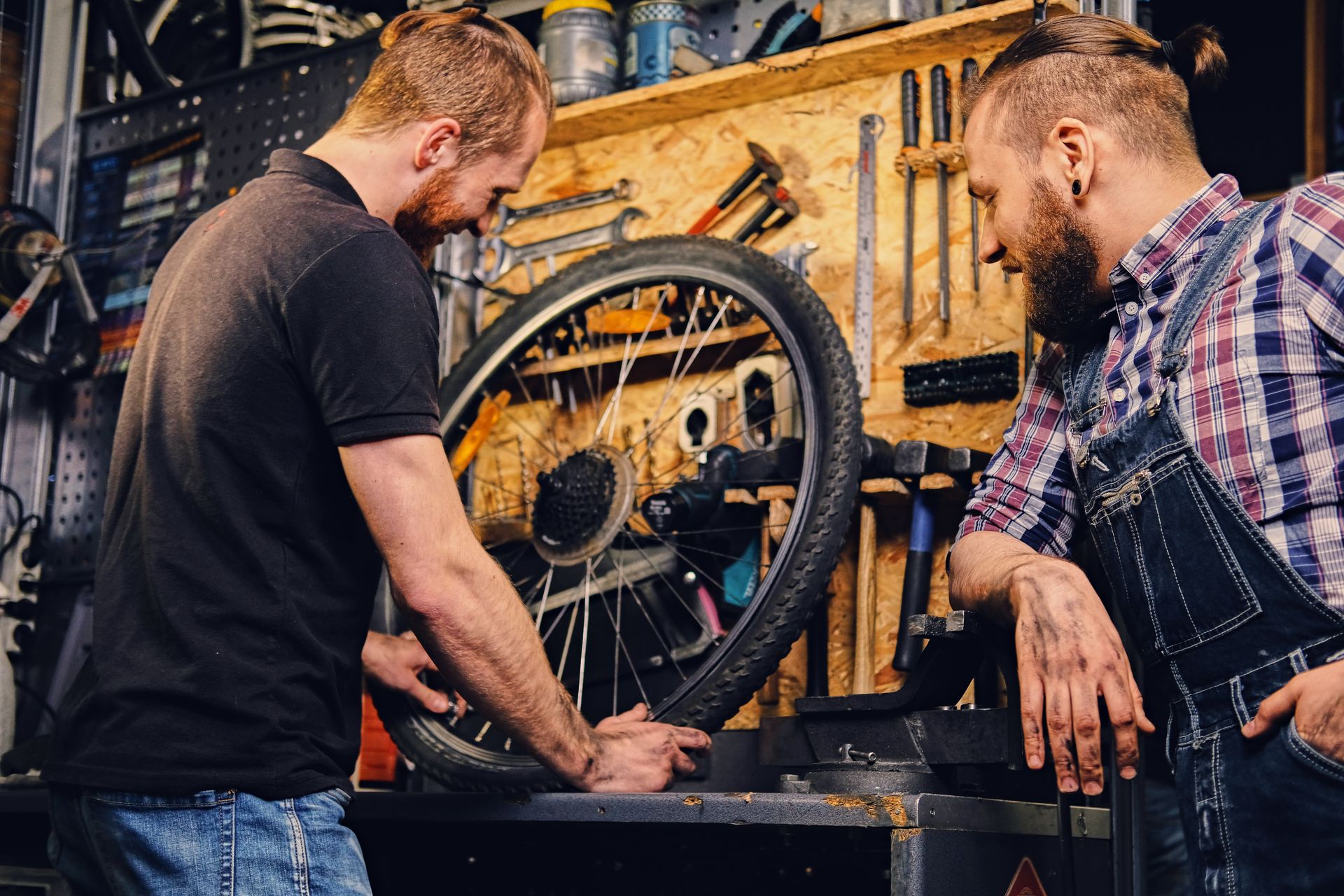 Two men are working on a bicycle tire in a garage.
