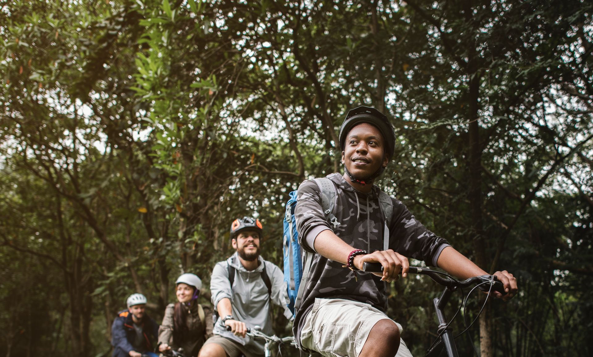 A group of people are riding bicycles through a forest.