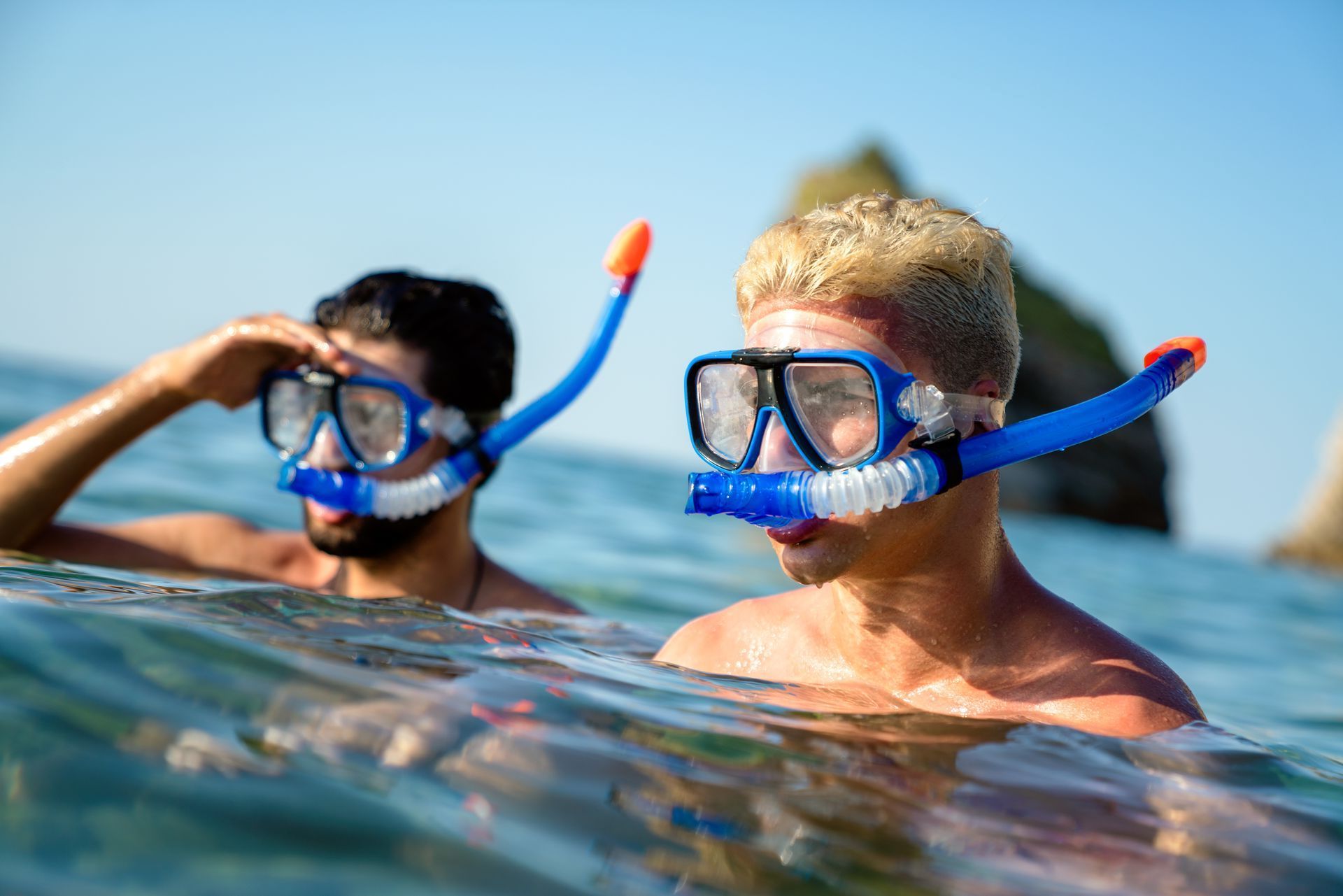 Two men are swimming in the ocean wearing snorkels.