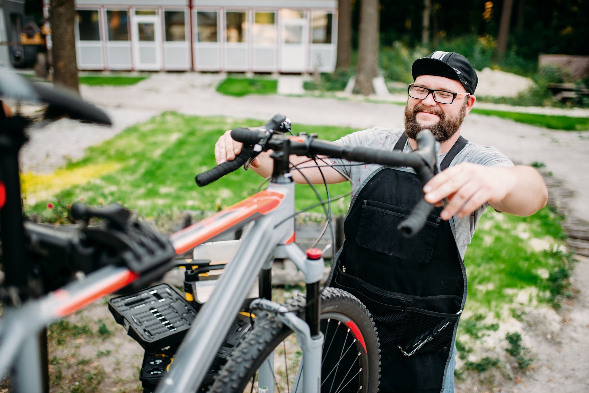A man is working on a bicycle in a park.