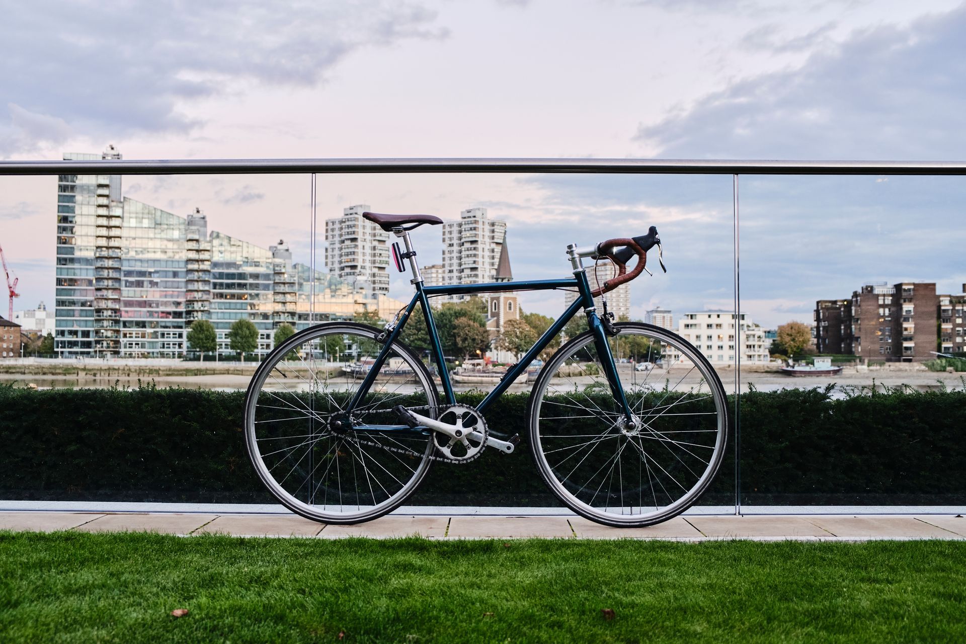 A bicycle is parked on the grass next to a railing.