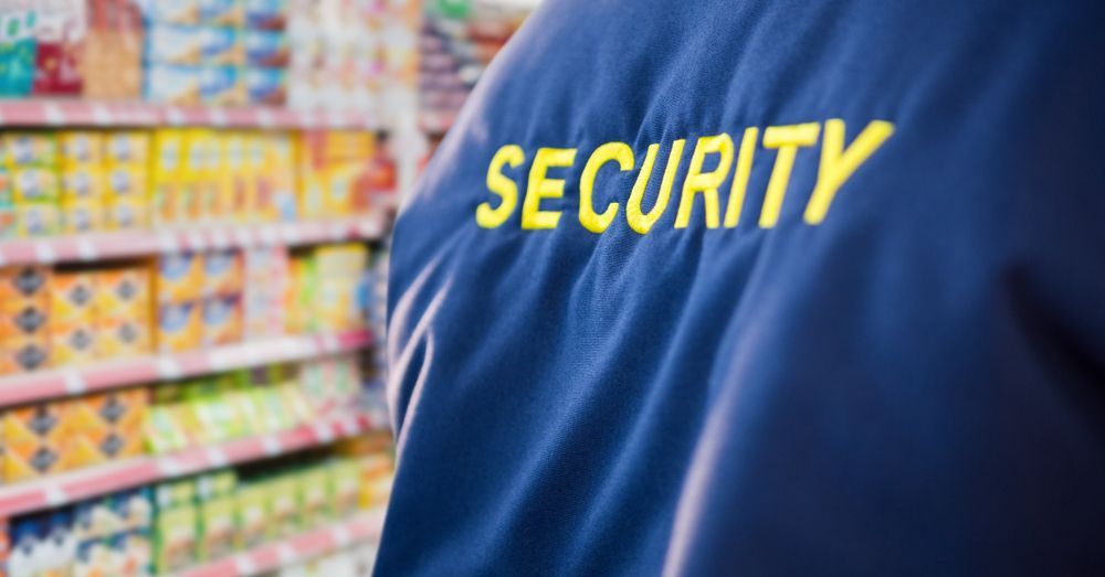 A security guard is standing in front of a supermarket aisle.