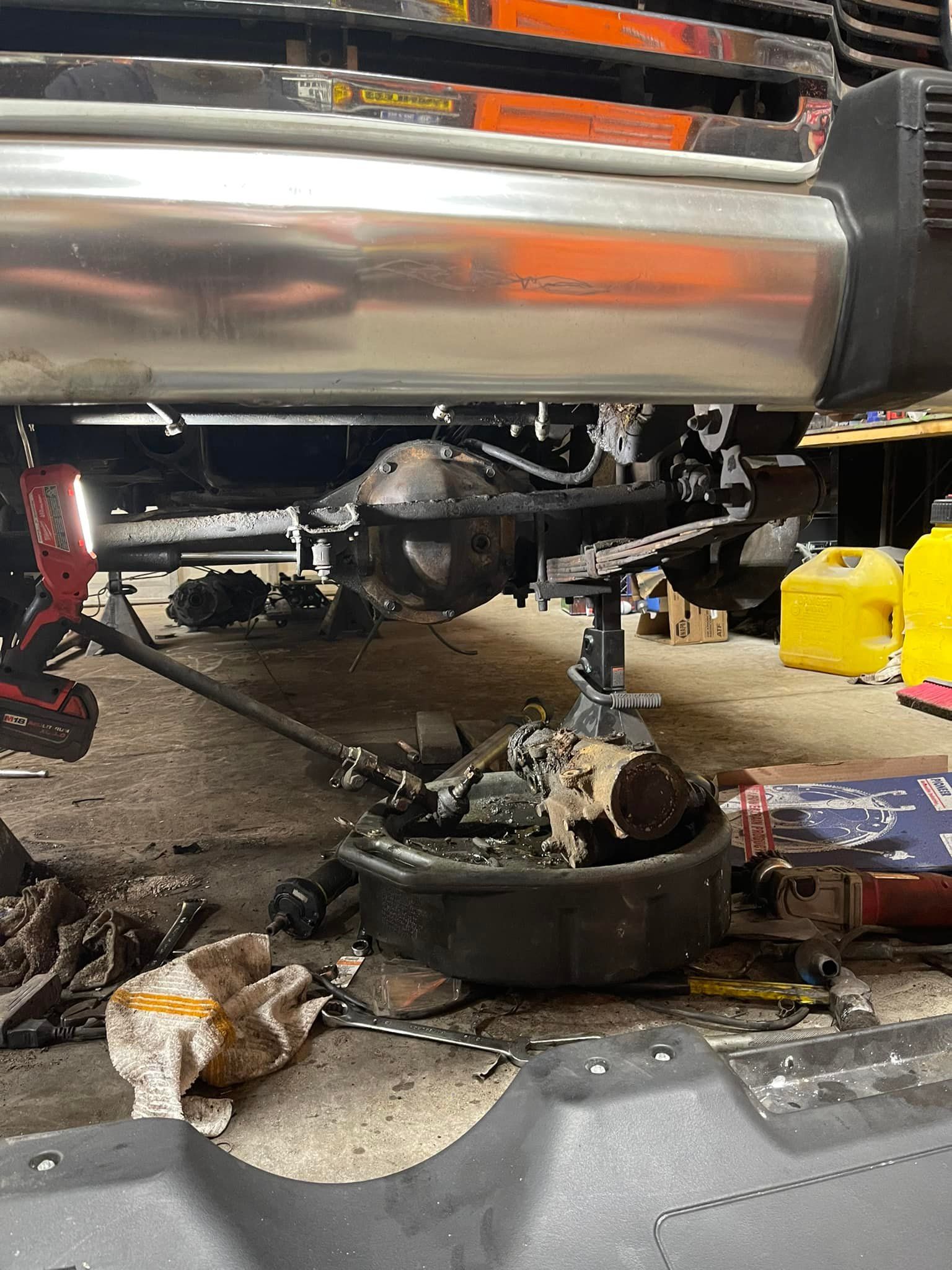 Undercarriage of a vehicle being worked on in a garage, with a differential and oil pan visible.