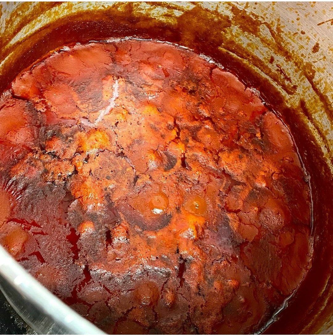 Un primo piano di una pentola di salsa con un cucchiaio dentro.