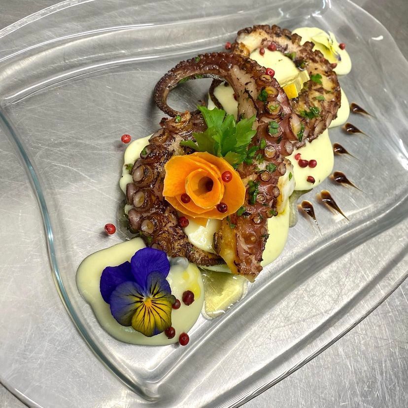 Un piatto di cibo con un polpo e dei fiori sopra