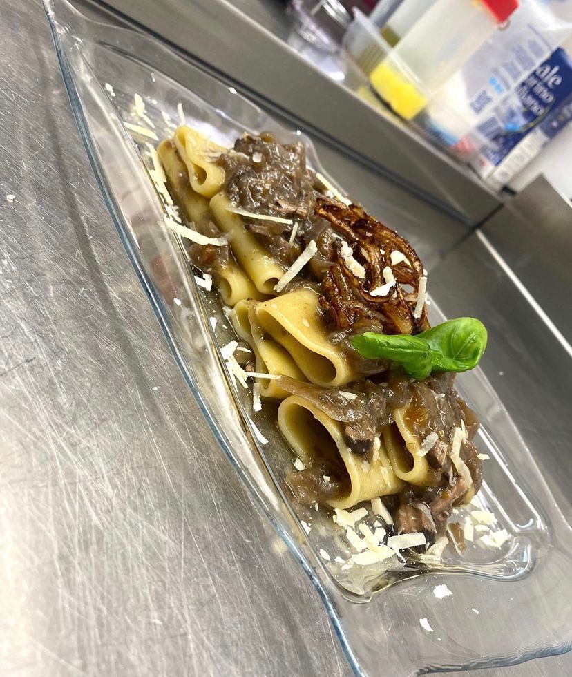 Un piatto di pasta con carne e formaggio su un tavolo