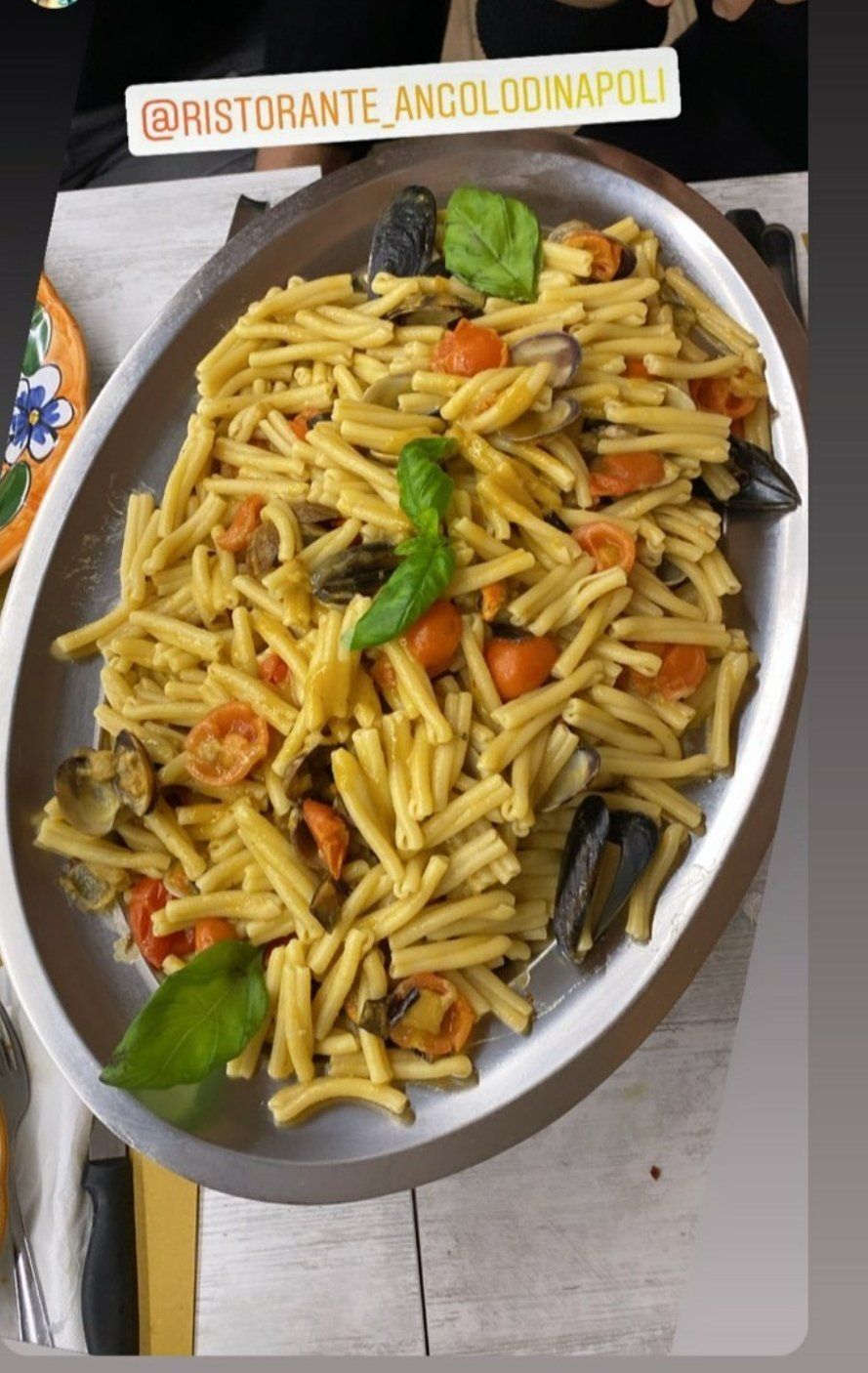 Un piatto di pasta con pomodori e basilico su un tavolo.