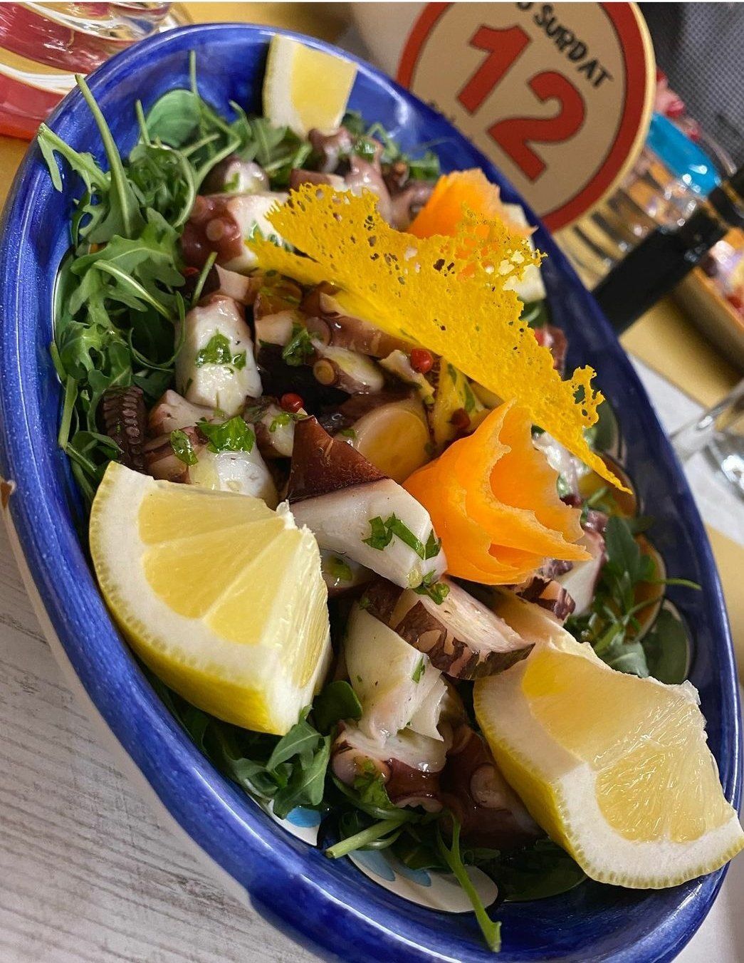 Una ciotola blu piena di verdure e fette di limone su un tavolo.