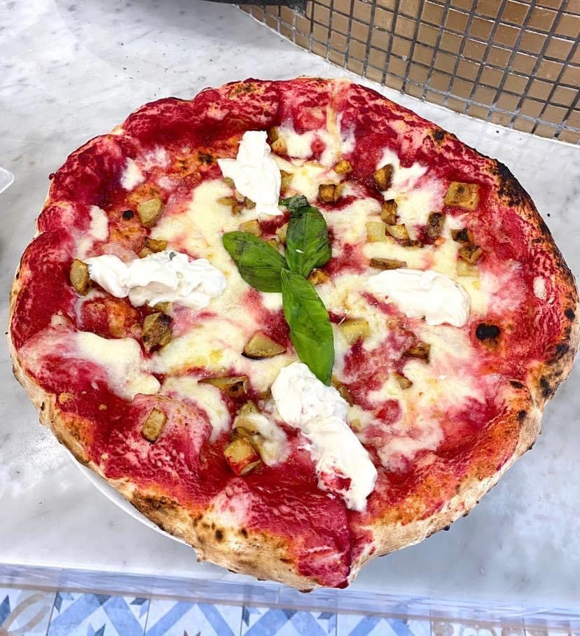 Una pizza è appoggiata su un piatto bianco su un tavolo.