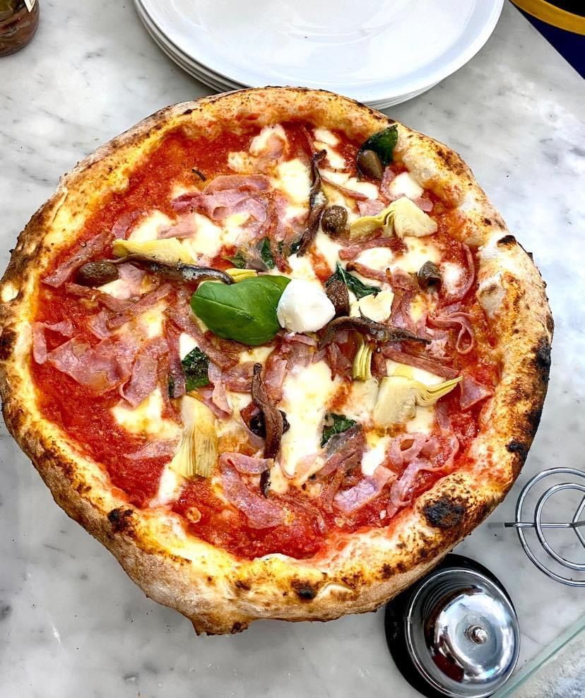 Una pizza con tanti condimenti è appoggiata su un tavolo.