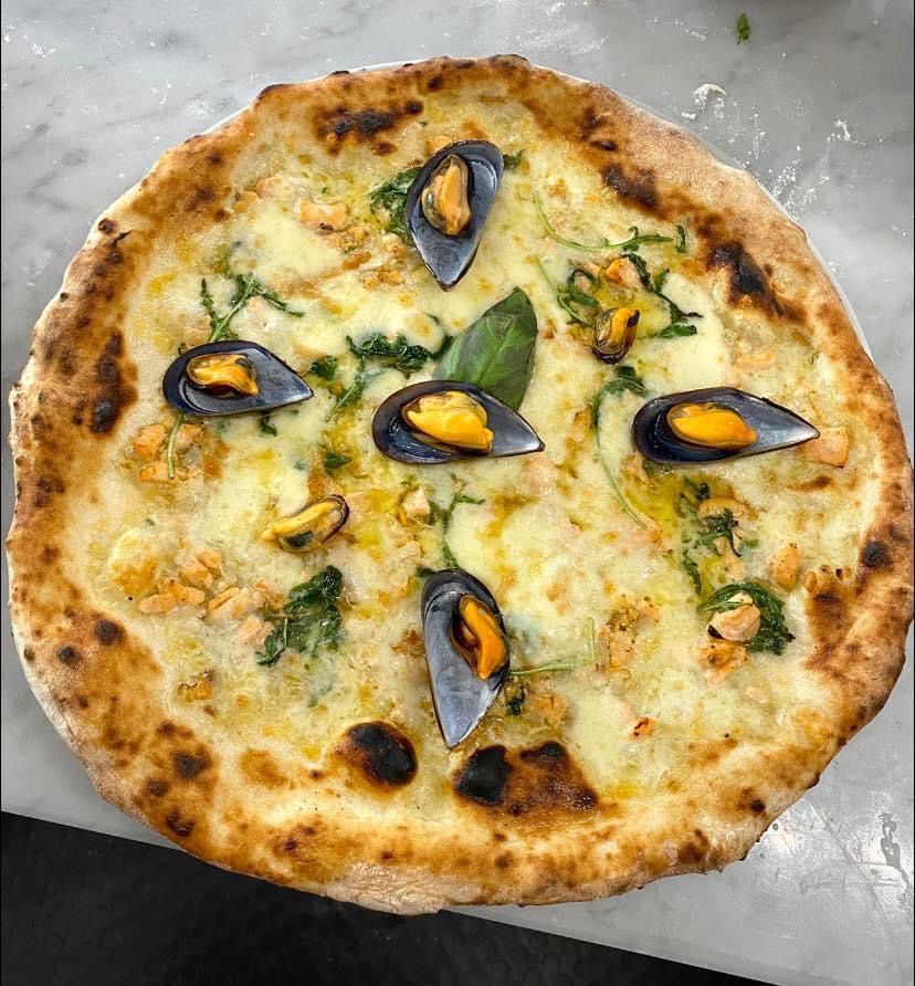 Una pizza con le cozze è appoggiata su un tavolo.
