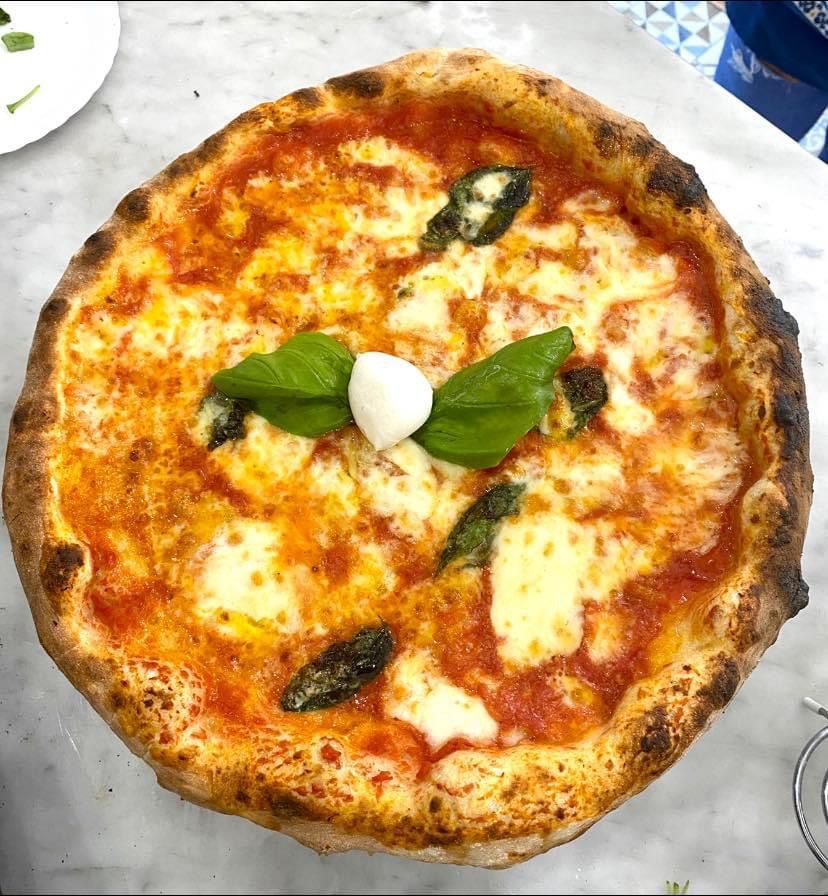 Una pizza margherita con formaggio e basilico sopra