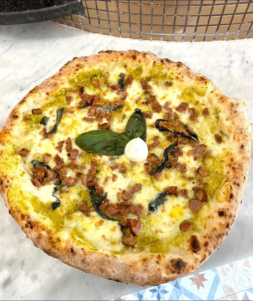 Una pizza con tanti condimenti è appoggiata su un tavolo.