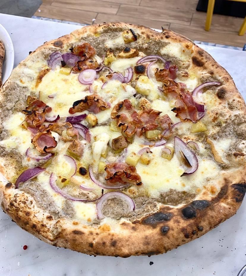 Una pizza con cipolle e pancetta sopra