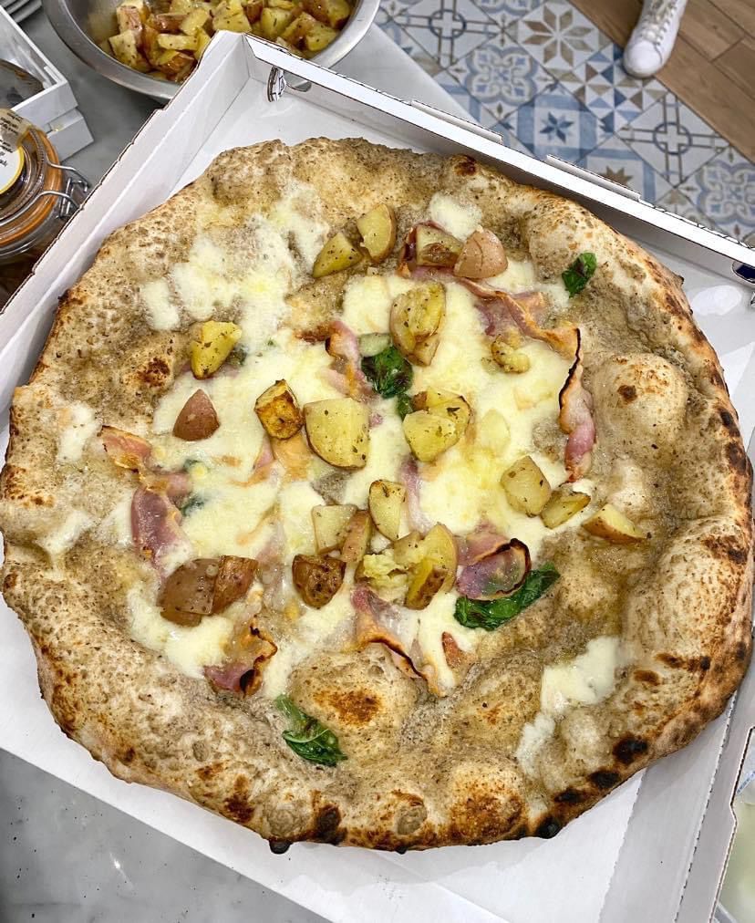 Una pizza bianca con patate in una scatola.