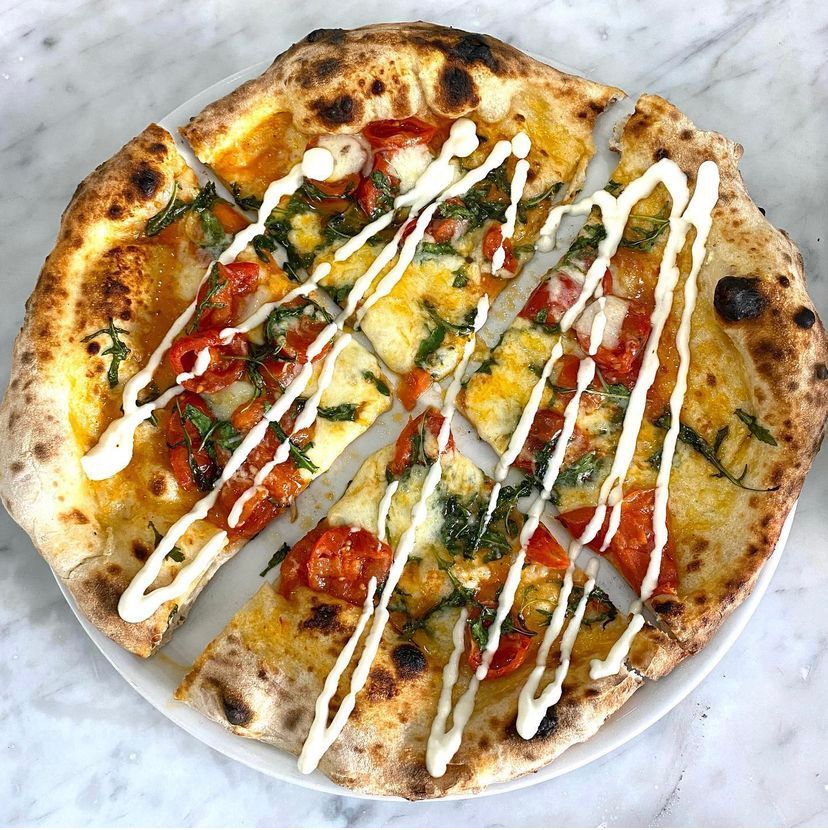 Una pizza con pomodori e formaggio su un piatto bianco