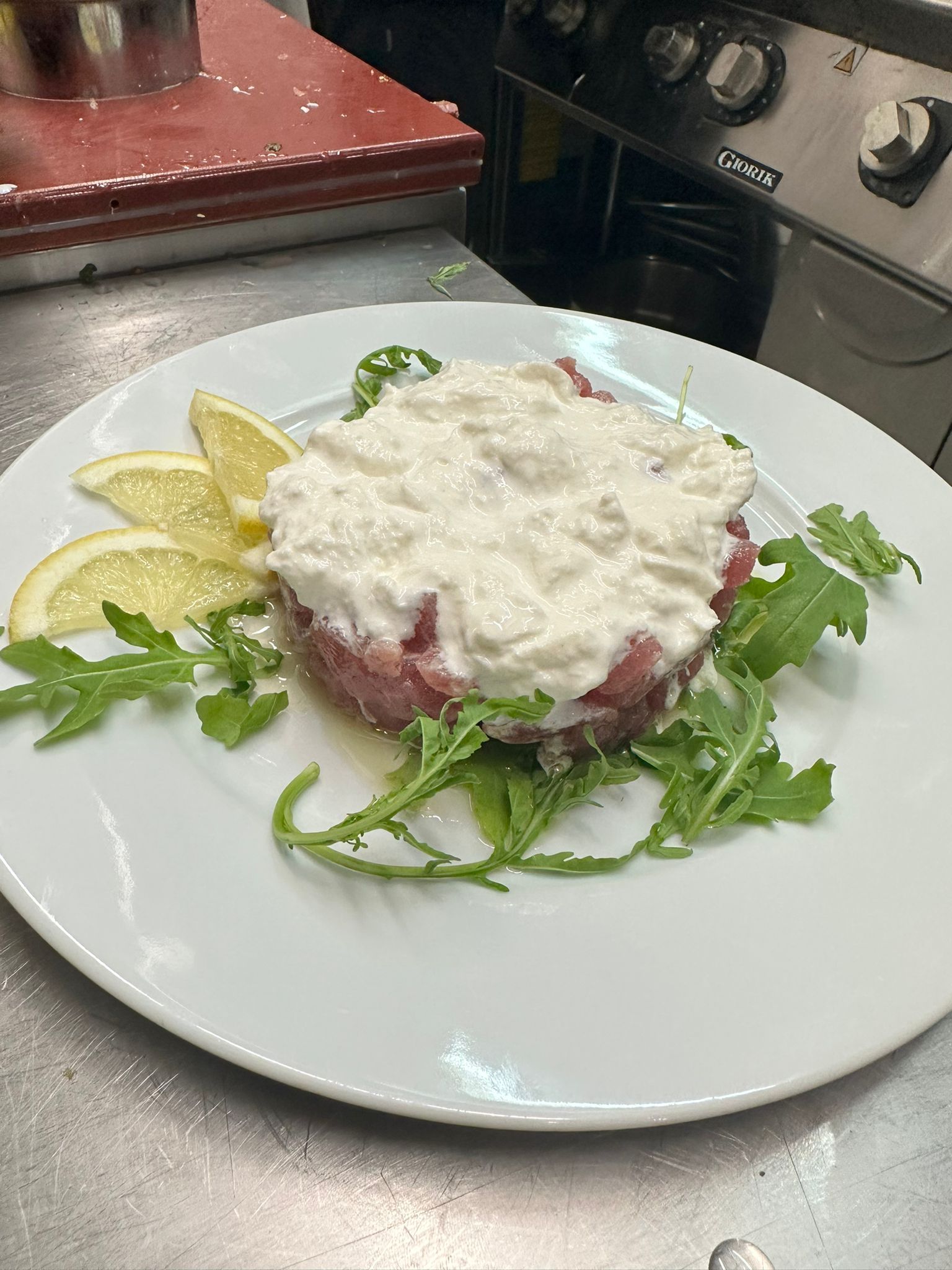 Un piatto bianco con sopra un pezzo di carne e salsa.