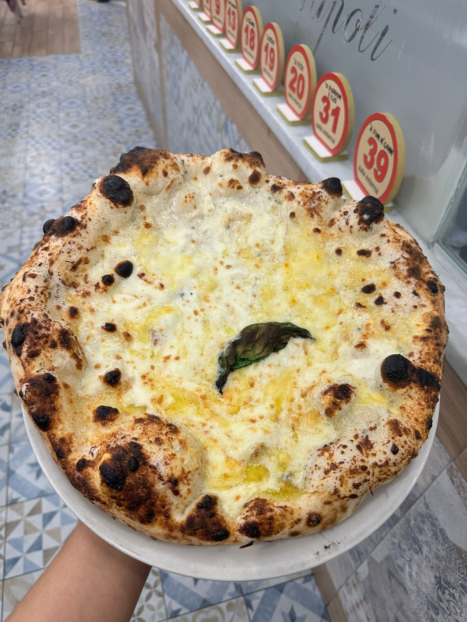 Una persona tiene in mano una pizza bianca su un piatto bianco.