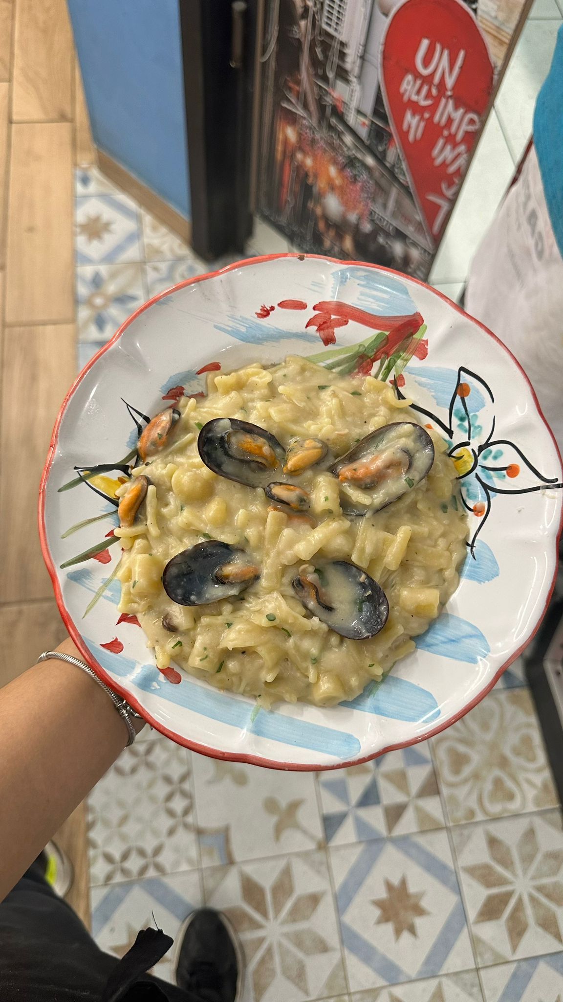 Una persona tiene in mano un piatto di cibo con sopra delle cozze.