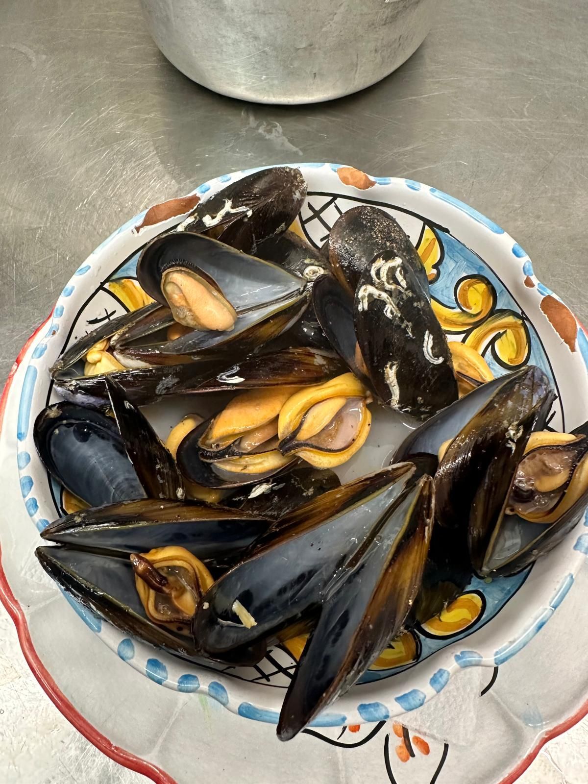 Un piatto di cozze è appoggiato su un tavolo.
