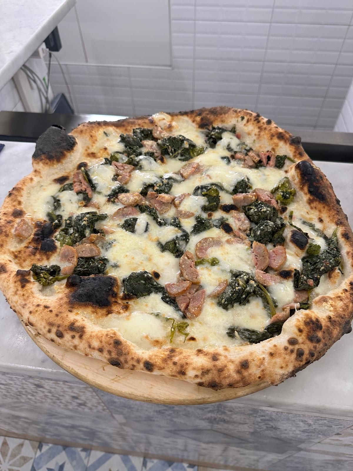 Una pizza con friarielli appoggiata su un tavolo.