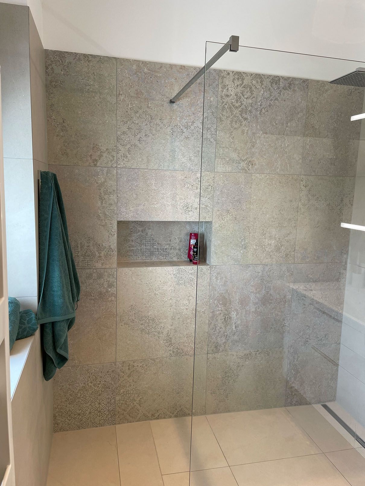 Ein Badezimmer mit ebenerdiger Dusche und einem an der Wand hängenden Handtuch.