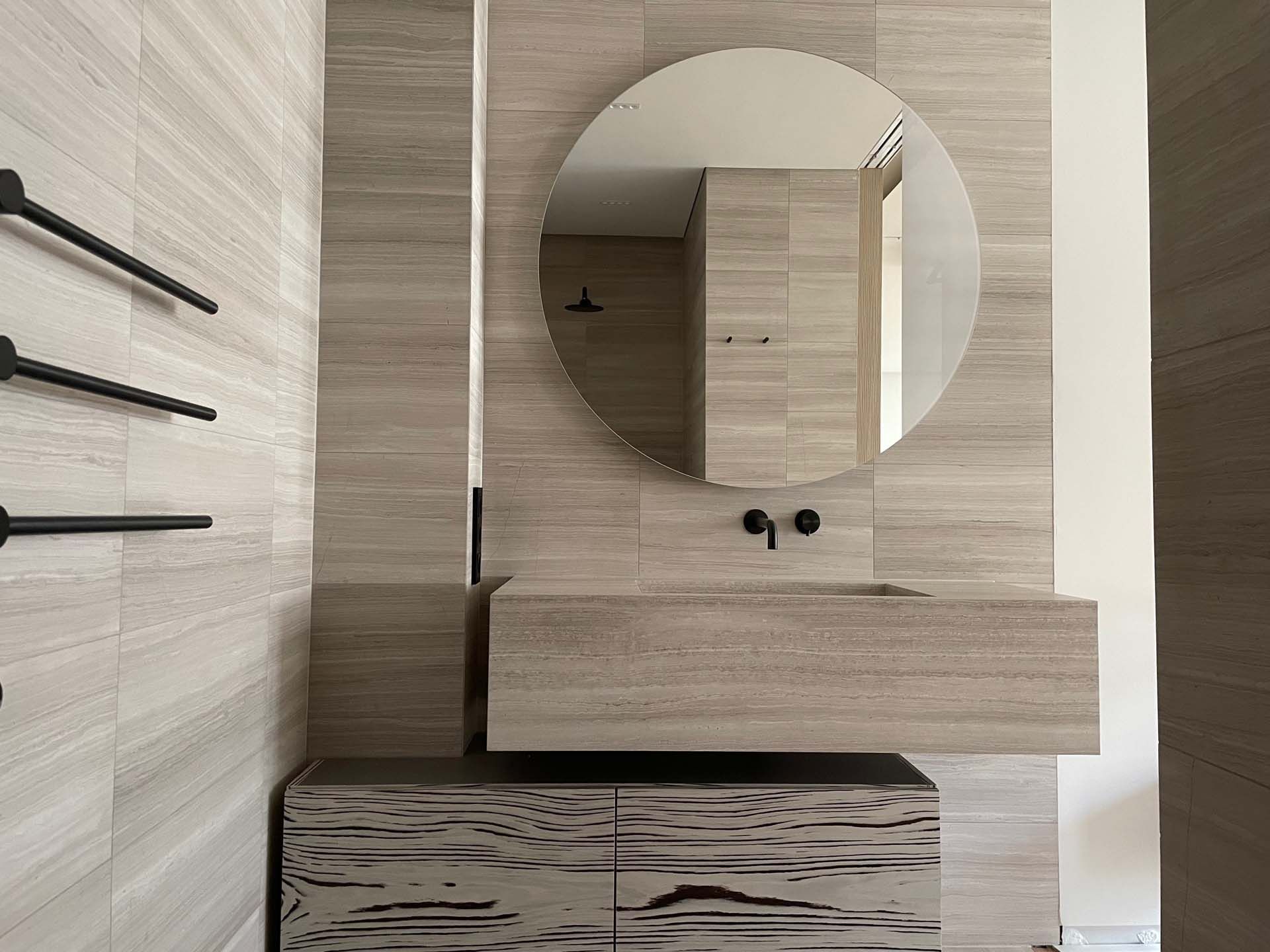 Ein Badezimmer mit Wandfliesen aus Holzoptik, mit Waschbecken, Spiegel und Handtuchhalter.