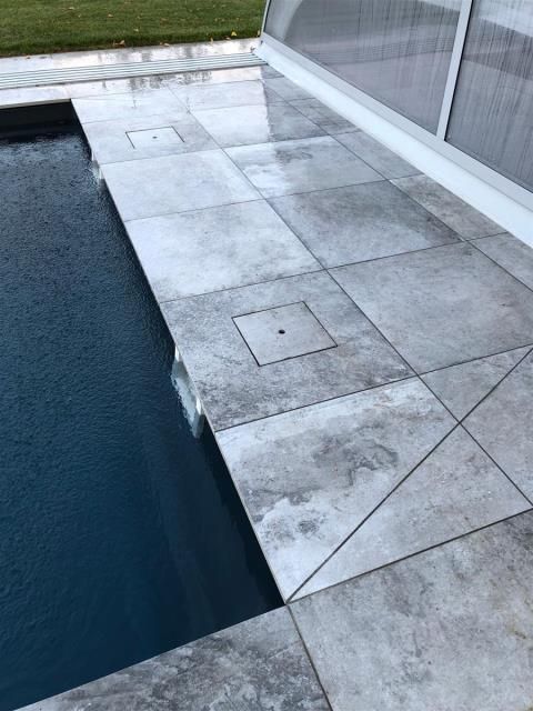 Ein Swimmingpool mit einer gefliesten Terrasse daneben