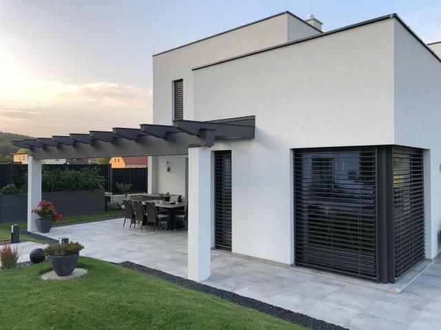 Ein weißes Haus mit einer Pergola und einer Terrasse davor