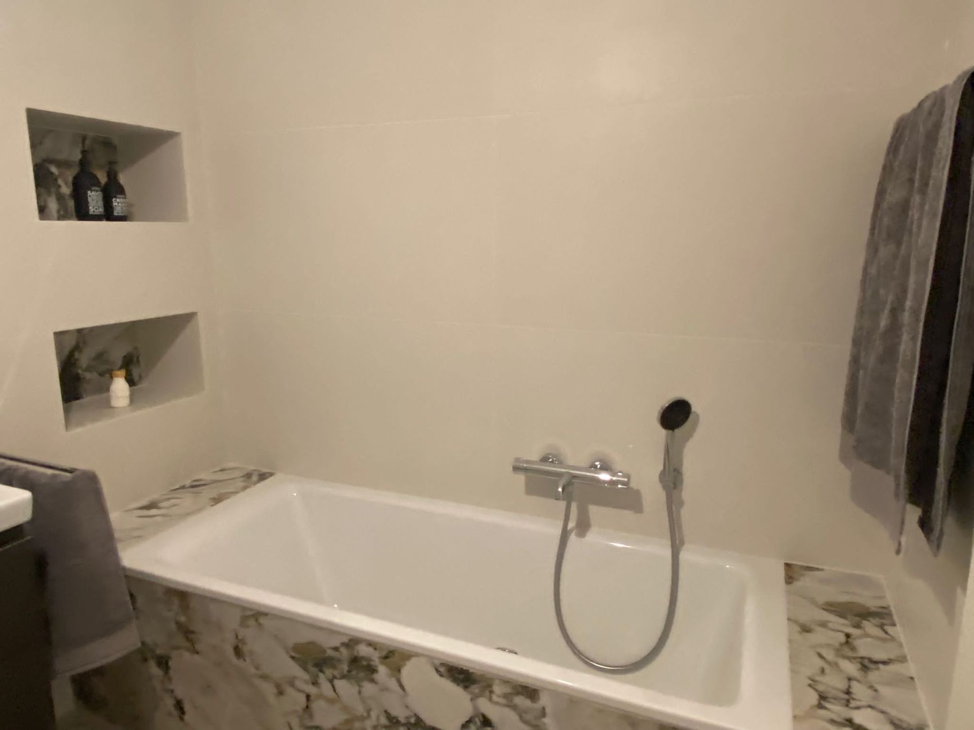 Ein Badezimmer mit ebenerdiger Dusche und Handtuchhalter.