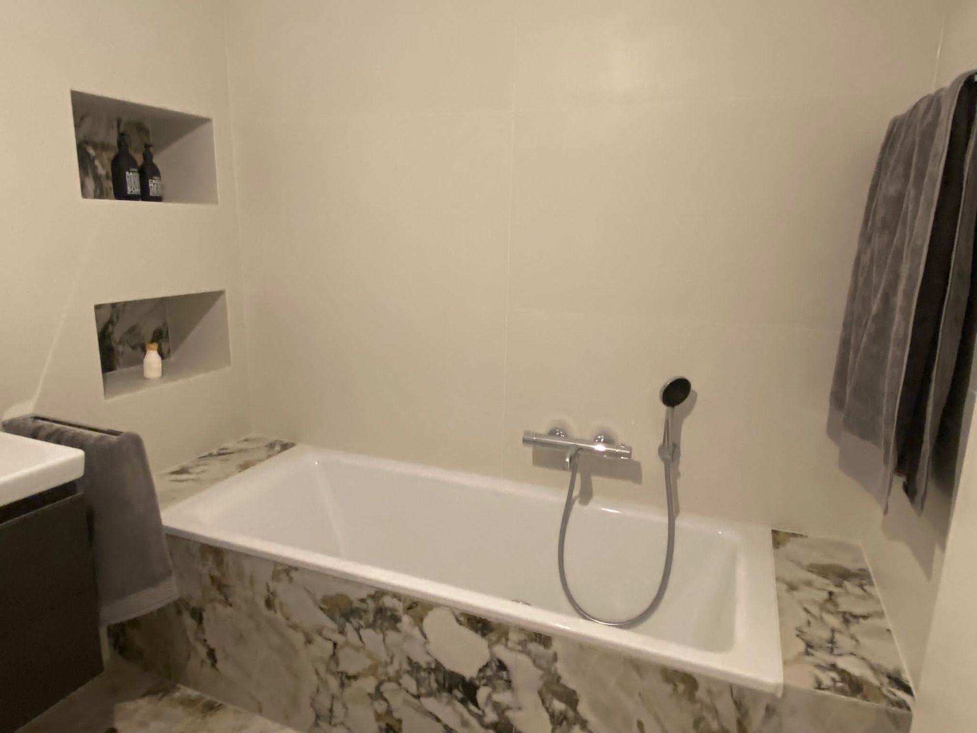 Ein Badezimmer mit Badewanne und speziellen Fliesen an der Wand.