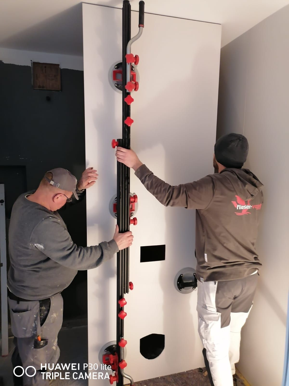 Zwei Männer bereiten eine Wand für die Fliesenverlegungen vor.