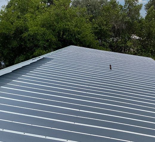 A close up of a metal roof with trees in the background.