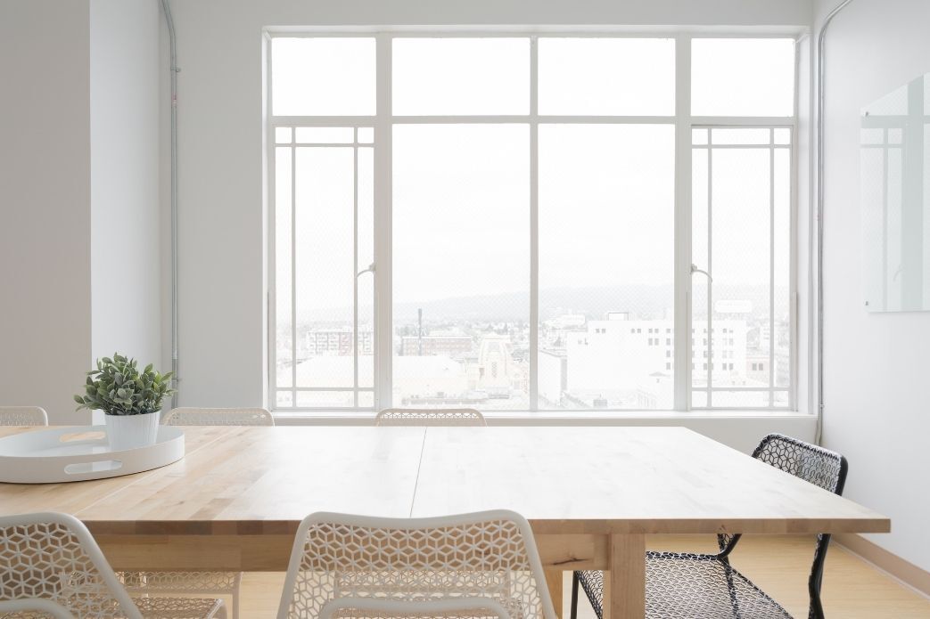 There is a table and chairs in the room with a large window.